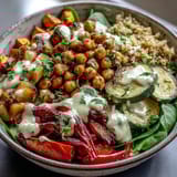A vibrant Roasted Chickpea Power Bowl topped with roasted vegetables and drizzled with tahini dressing.