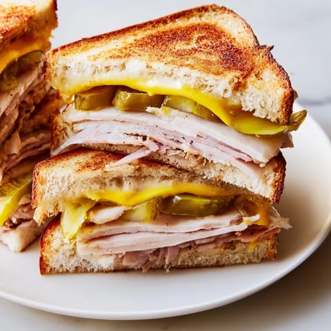 Golden-brown Cuban Sandwich, pressed until melty, filled with savory pork, ham, and Swiss cheese.