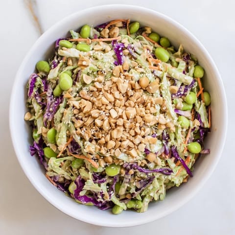 Crunchy Thai Peanut Salad topped with roasted peanuts, sesame seeds, and lime wedges, perfect for a refreshing light meal.  