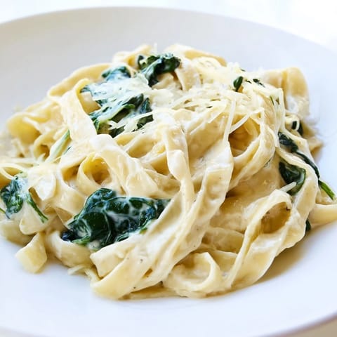 Creamy Garlic Spinach Pasta fettuccine tossed with wilted baby spinach in a velvety garlic cream sauce, garnished with fresh parsley.