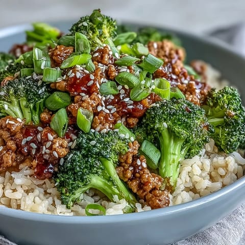 A serving of Sweet and Spicy Turkey Broccoli Bowls garnished with fresh green onion and sesame seeds.