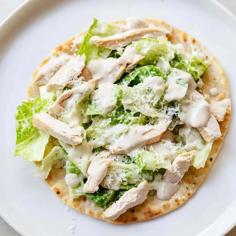 A slice of Chicken Caesar Flatbread with juicy chicken, fresh romaine, and tangy Caesar sauce.