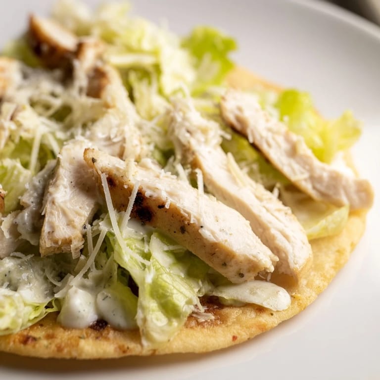 Serving suggestion for Chicken Caesar Flatbread with chopped romaine, grilled chicken, and shaved parmesan.