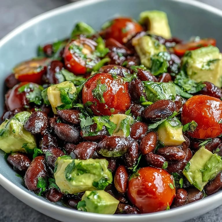 Healthy, colorful black bean and veggie bowl featuring sweet corn, juicy tomatoes, and creamy avocado in a lime-cumin dressing.  