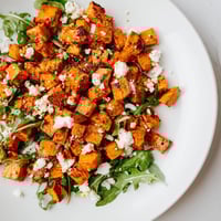 Roasted Sweet Potato Salad with golden cubes, peppery arugula, and crumbled feta, all dressed in honey-lime vinaigrette.