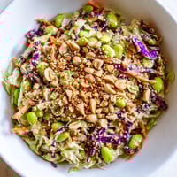 Vibrant bowl of Crunchy Thai Peanut Salad with shredded cabbage, carrots, and edamame tossed in creamy peanut dressing.  
