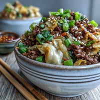 Ground pork and cabbage slaw sautéed for a savory Egg Roll in a Bowl, topped with fresh green onions.